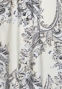 Tissu beige avec un motif cachemire complexe en noir, marron et blanc, comprenant des motifs floraux et des volutes abstraites.
