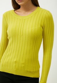 Maglione giallo a coste con maniche lunghe, scollatura rotonda e motivo verticale testurizzato lungo i lati. Presenta un design aderente.