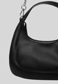 Borsa a tracolla in pelle nera con una maniglia corta e chiusura in tonalità argento su uno sfondo grigio chiaro.