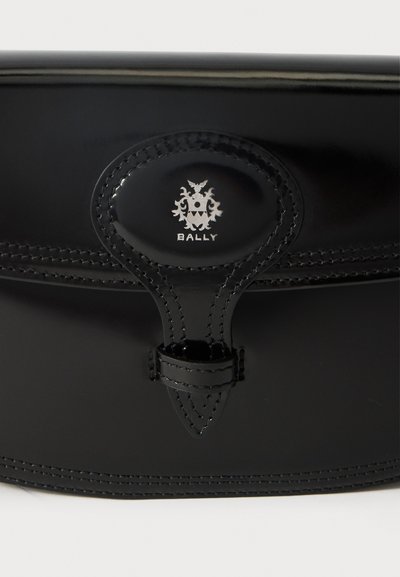 Black leather bag featuring a prominent oval clasp with a silver emblem. Stitched detailing along the edges, with a smooth, glossy finish.