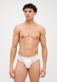 Bóxers blancos para hombres con un diseño ajustado, cinturilla elástica con marca en negro y rojo, y una textura de material lisa.