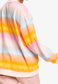 Sudadera oversized de manga larga en tonos degradados pasteles de rosa, azul y amarillo. Presenta una tela suave y texturizada, con mangas acampanadas.