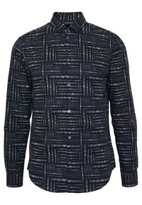 Camisa negra abotonada con un patrón tipográfico repetido que muestra "Emporio Armani" en diversas fuentes, mangas largas y un cuello clásico.