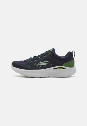 Zapatilla de running de color navy con parte superior de malla, acentos en verde neón y suela blanca. Cuenta con un diseño de cordones y un acolchado estructurado para ofrecer soporte.