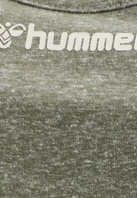 Tissu en mélange de coton vert olive avec une texture marbrée. Présente un logo blanc "hummel" en haut, avec un col rond.