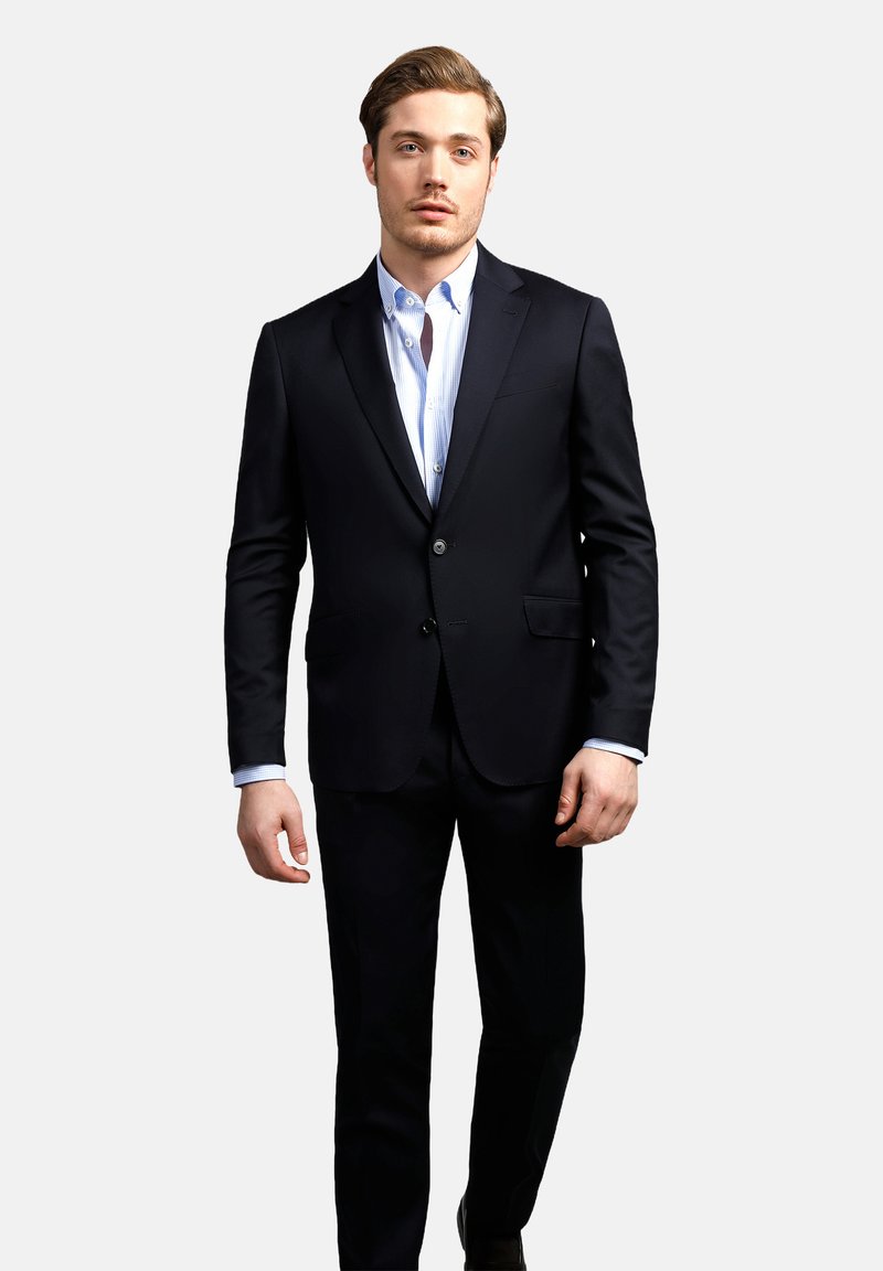 Marineblaues Anzug mit taillierter Passform, ausgestattet mit einer Zwei-Knopf-Verschluss und Reverskragen, kombiniert mit einem hellblauen, gestreiften Button-Up-Hemd.