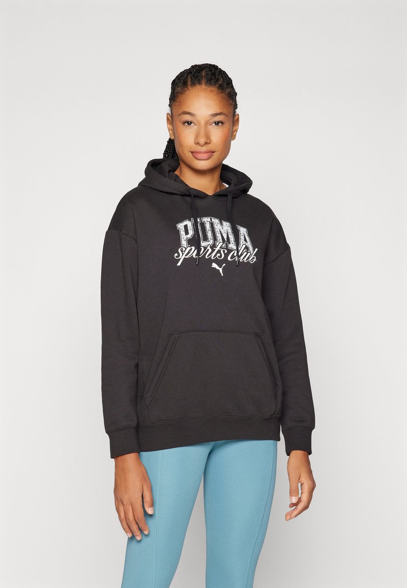 Felpa nera con cappuccio con stampa "PUMA sports club", tasca frontale e polsini a coste, abbinata a leggings azzurri chiari.