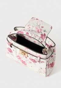 Bolso blanco con patrón floral rosa, cierre dorado, asa superior y solapa abierta que revela el forro interior negro.