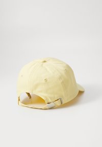 Geel katoenen baseballcap met een ronde kroon, verstelbare metalen sluiting aan de achterkant en ventilatiegaten aan de zijkanten.