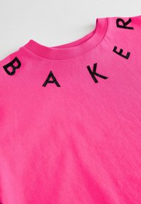 Lyserød bomulds T-shirt med ordet "BAKER" i sorte glitrende bogstaver langs udfordringen. Glat tekstur og klassisk crew neck design.