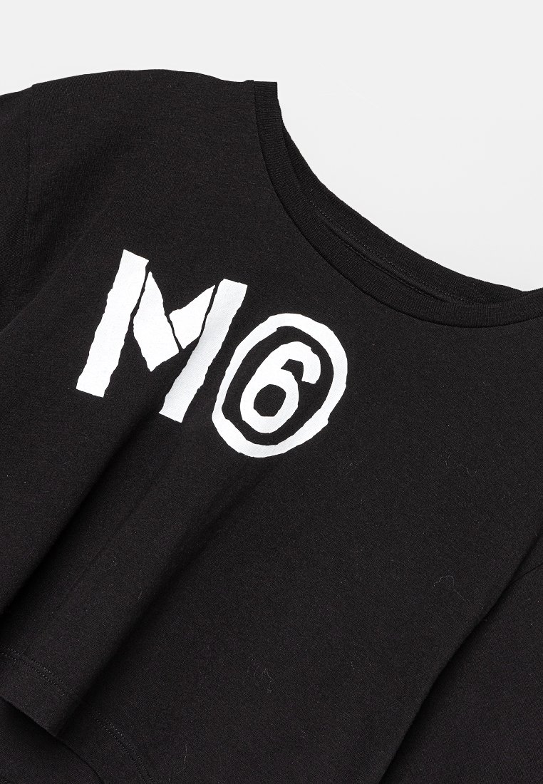 T-shirt nera cropped in cotone, con testo grafico bianco "M" e "6" racchiusi in un contorno circolare. Texture morbida e vestibilità rilassata.