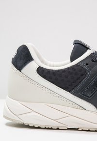 Pánské sneakers v tmavě námořnické síťovině a kůži, s bílou gumovou podrážkou. Mají polstrovaný límec a kontrastní světle šedé akcenty.