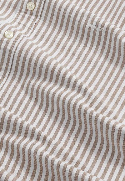 Tkanina w pionowe biało-beżowe paski z trzema białymi guzikami i subtelnym haftowanym napisem w prawym górnym rogu.