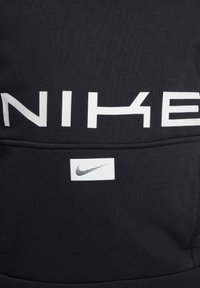 Svart sweatshirt med fet vit "NIKE" logotyp framtill och en liten vit Nike swoosh etikett nära fickan. Mjuk tygkänsla.