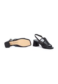 Tacones de slingback negros con un revestimiento de malla, puntera cuadrada y un tacón grueso. Presenta un cierre de cremallera en la parte posterior y una suela plana.