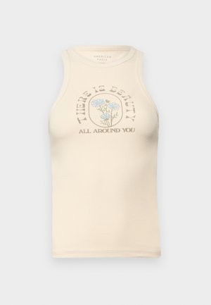 Top de tirantes ajustado color beige con un escote alto y sin mangas. Presenta un gráfico floral impreso y el texto: "HAY BELLEZA A TU ALREDEDOR."