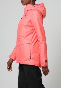 Korallfärgad vattentät jacka med huva, fickor framtill med dragkedja och justerbara ärmslut. Strukturerad tyg med ett subtilt randmönster.