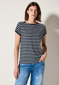 T-shirt à rayures bleu marine et blanches, à manches courtes, col rond et coupe décontractée, associé à un jean en denim bleu clair. Texture lisse.