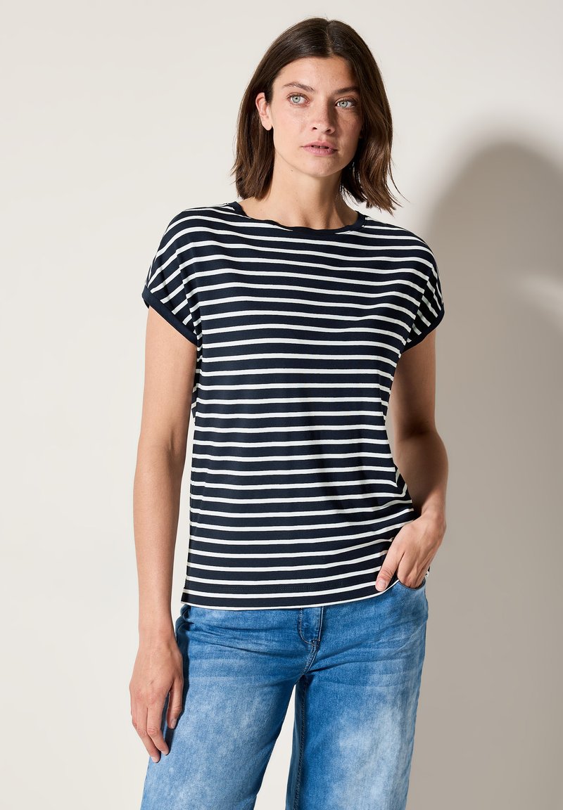 T-shirt à rayures bleu marine et blanches, à manches courtes, col rond et coupe décontractée, associé à un jean en denim bleu clair. Texture lisse.