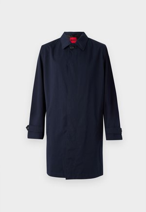 Granatowy płaszcz trench z spiczastym kołnierzem, zapięcie na jeden guzik i podwijane rękawy z guzikowymi akcentami. Gładka tekstura, minimalistyczny design.