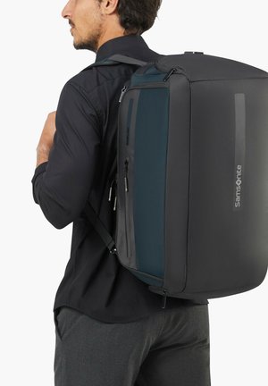 Black and teal backpack with a sleek design, featuring zippers, adjustable straps, and a durable texture suitable for daily use.