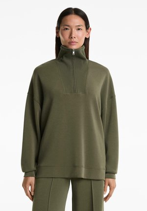 Olijfgroene sweatshirt met een hoge kraag en halve rits, voorzien van een textuurpaneel en verlaagde schouders voor een ontspannen pasvorm.
