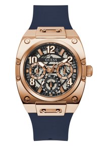Guld-tone ur med en marineblå silikonestraps, sort tekstureret urskive, fede hvide og guld tal, og flere kronograf underdials.