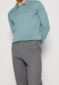 Světle modrá polokošile s dlouhým rukávem a třemi knoflíky, spárovaná se šedými skinny kalhotami s hladkou texturou a kapsami.