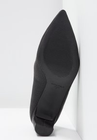 Chaussure à talons hauts noire avec une surface texturée. Dotée d'un bout pointu et d'une semelle nervurée. Comprend le logo "ANNA FIELD" sur la semelle. Taille 37.