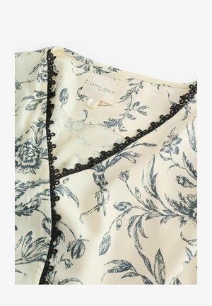 Blusa di tessuto crema con un motivo floreale scuro, bordo in pizzo nero lungo il colletto e etichetta con la scritta "Laura Ashley."