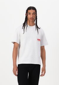 Gray cotton t-shirt with a crew neckline and short sleeves, featuring a red printed logo on the left chest. Textured fabric, relaxed fit.