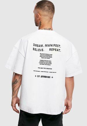 White oversized t-shirt featuring black text on the back, with motivational phrases and branding for "2Y STUDIOS"; cotton material, casual fit.