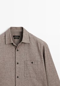 Brun, knappet skjorte lavet af tekstureret stof med en brystlomme, sorte knapper og et klassisk kravedesign.