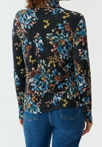 Langärmliges, tailliertes Oberteil in Schwarz mit einem bunten Blumenmuster, das blaue, pinke und gelbe Blätter zeigt. Weicher Stoff mit glatter Textur.