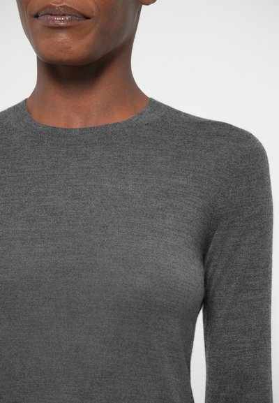 Siv svetar iz pletene tkanine z okroglo izrezano ovratnikom in dolgimi rokavi, izdelan iz mehkega, teksturiranega materiala z gladko površino.
