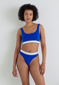 Blå bomullsbralette og truse-sett med hvit elastisk midje. Har et enkelt design og en glatt tekstur.
