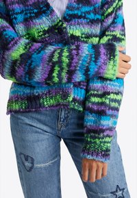 Cardigan en maille avec un motif de rayures verticales multicolores en bleu, vert et violet. Présente une fermeture à boutons et des poignets côtelés.
