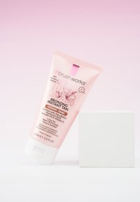 Tube rose de bronzage instantané Brush Works, teinte médium-foncé, avec des accents blancs, 150 mL, arborant un design floral et des détails d'étiquette clairs.