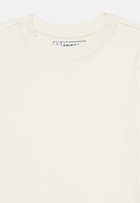 Μπεζ βαμβακερό μπλουζάκι με στρογγυλή λαιμόκοψη, κοντά μανίκια και ομαλή υφή. Η ετικέτα στο εσωτερικό γράφει "FRIBOS" και το μέγεθος είναι 5/6 ετών.