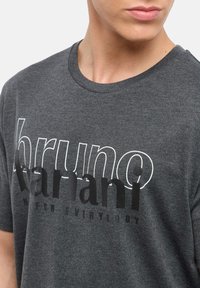 Grijze katoenen t-shirt met een ronde halslijn, voorzien van de merknaam "bruno" in het wit en "banani" in vet zwart schrift over de borst.