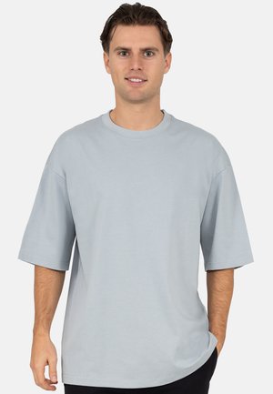 Light blue oversized t-shirt made from soft fabric. Features short sleeves, a crew neckline, and a relaxed fit. Seam detailing on shoulders.