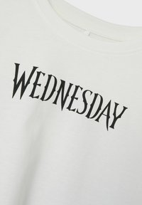 Hvid bomulds t-shirt med ordet "ONSDAG" i fed, sort, stiliseret skrift. Klassisk crew neck design. Blød tekstur.