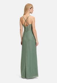 Długa zielona sukienka o błyszczącej fakturze, z dopasowanym gorsetem, skrzy żowanymi ramiączkami i zwiewną spódnicą.