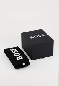 Black box with a glossy finish and white "BOSS" logo, paired with a matching black pouch featuring the logo in white.