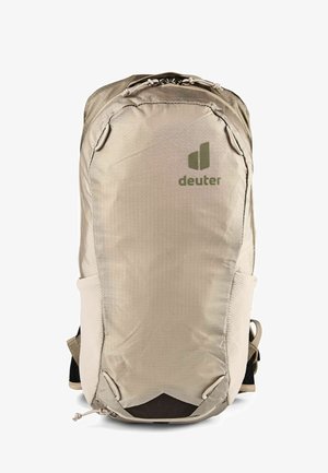 Sac à dos beige Deuter avec poche zippée à l'avant, poches latérales en mesh et poignée supérieure, conçu pour la randonnée ou un usage quotidien.