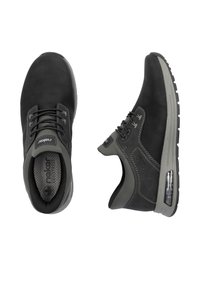 Baskets décontractées noires et grises avec fermeture à lacets, col rembourré et coussin d'air visible dans la semelle, vues de dessus et de côté.