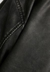 Černá kožená látka s hladkou texturou, jemným vzorem zrna a viditelnými švy, se jemným leskem typickým pro kožené výrobky.