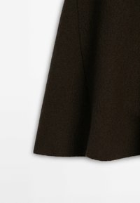 Tissu en laine marron foncé d'une manche de vêtement avec une finition douce et texturée sur un fond clair.