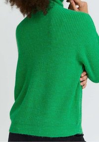 Grüner Rollkragenpullover aus strukturiertem Strickstoff. Verfügt über eine lockere Passform, gerippten Halsausschnitt und seitliche Schlitze für zusätzlichen Komfort.
