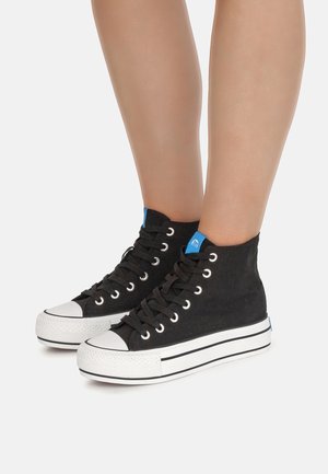 Zapatillas altas negras de lona, con suelas y punteras de goma blanca, cordones negros y detalles azules en la lengüeta.